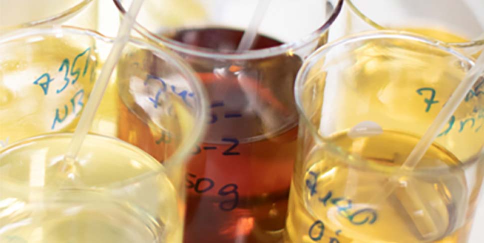 Several yellowish and one red liquid samples in round jars