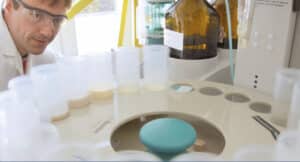 A man in the lab wearing safety goggles looks at sample containers rotating in a machine