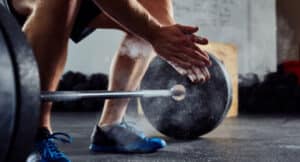 One person kneels in front of barbells